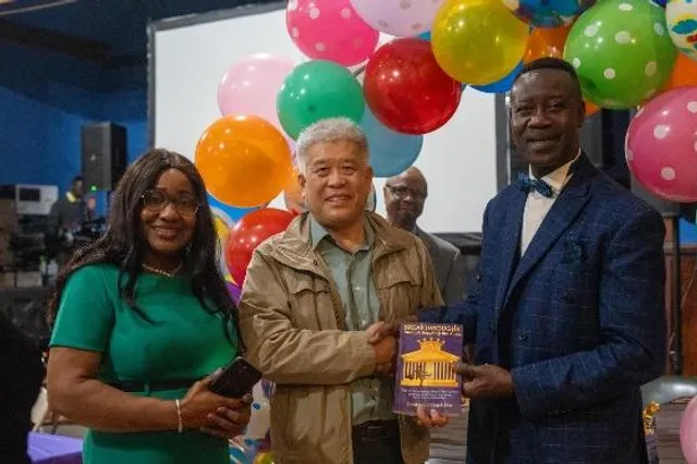 Chuck Eke presenting a copy of Breakthroughs Through Breaking the Rules at a book event