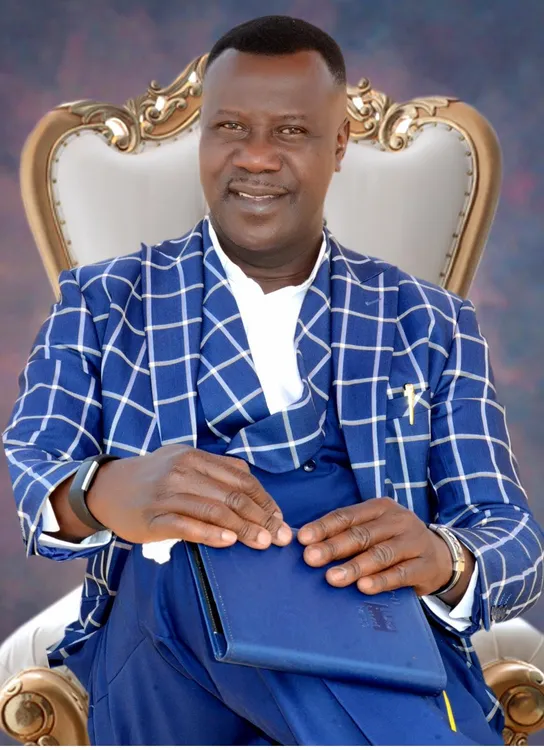 Ambassador (Rev.) Chukwudi Eke, seated formal portrait in a blue windowpane suit